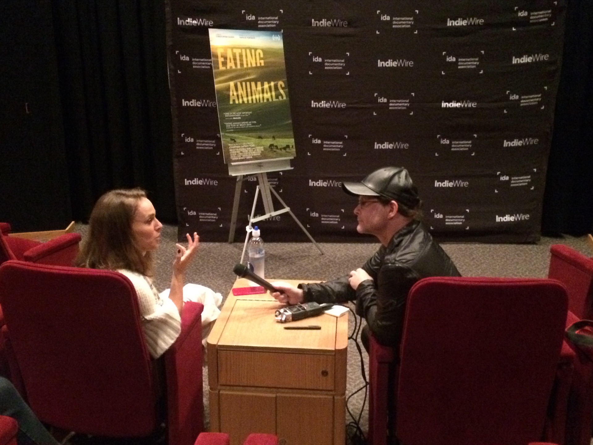 Eating Animals talent sits for a press interview in front of the IndieWire and International Documentary Association step-and-repeat.