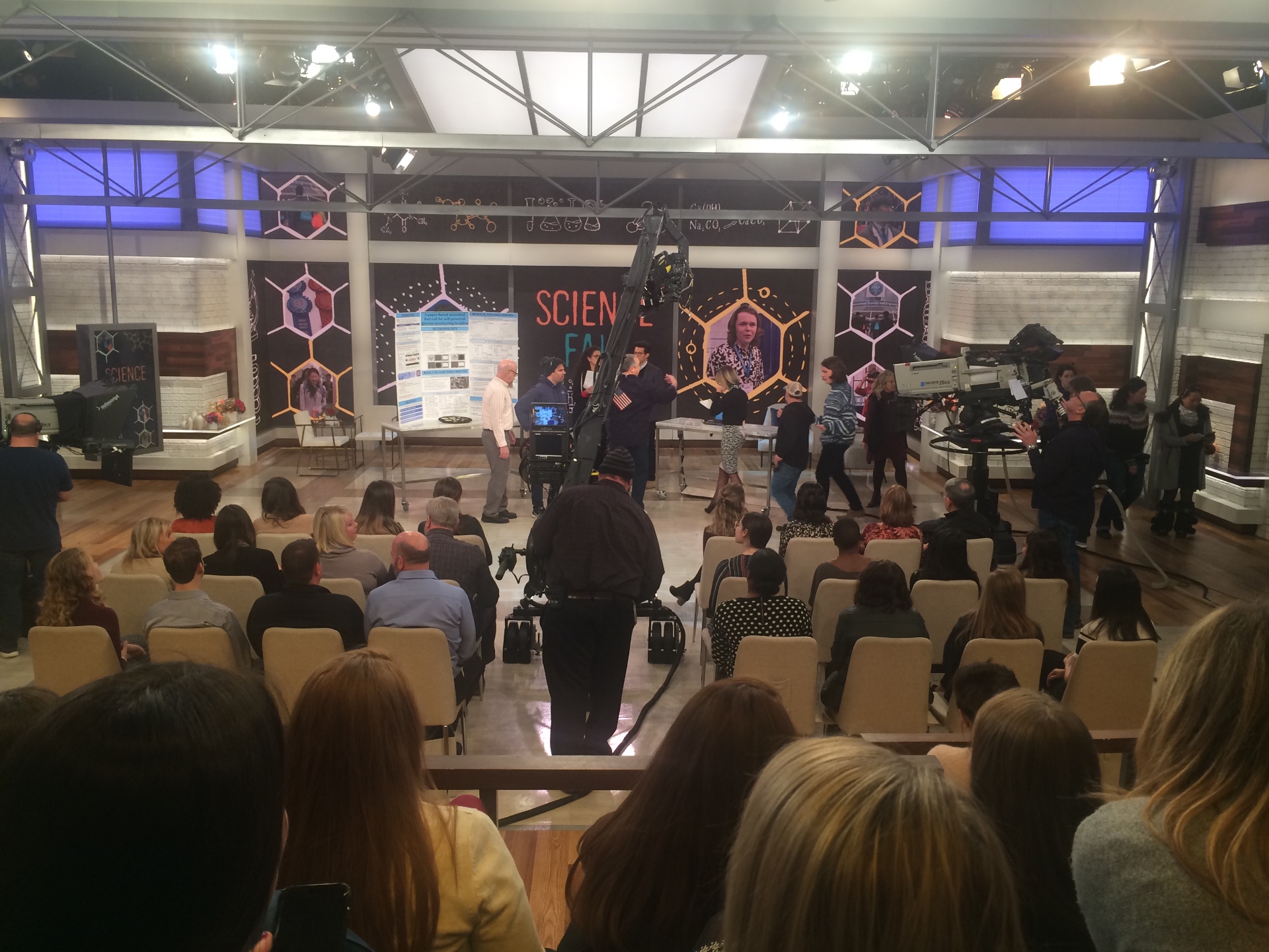 Live studio audience and broadcast crew during a Science Fair television segment taping.