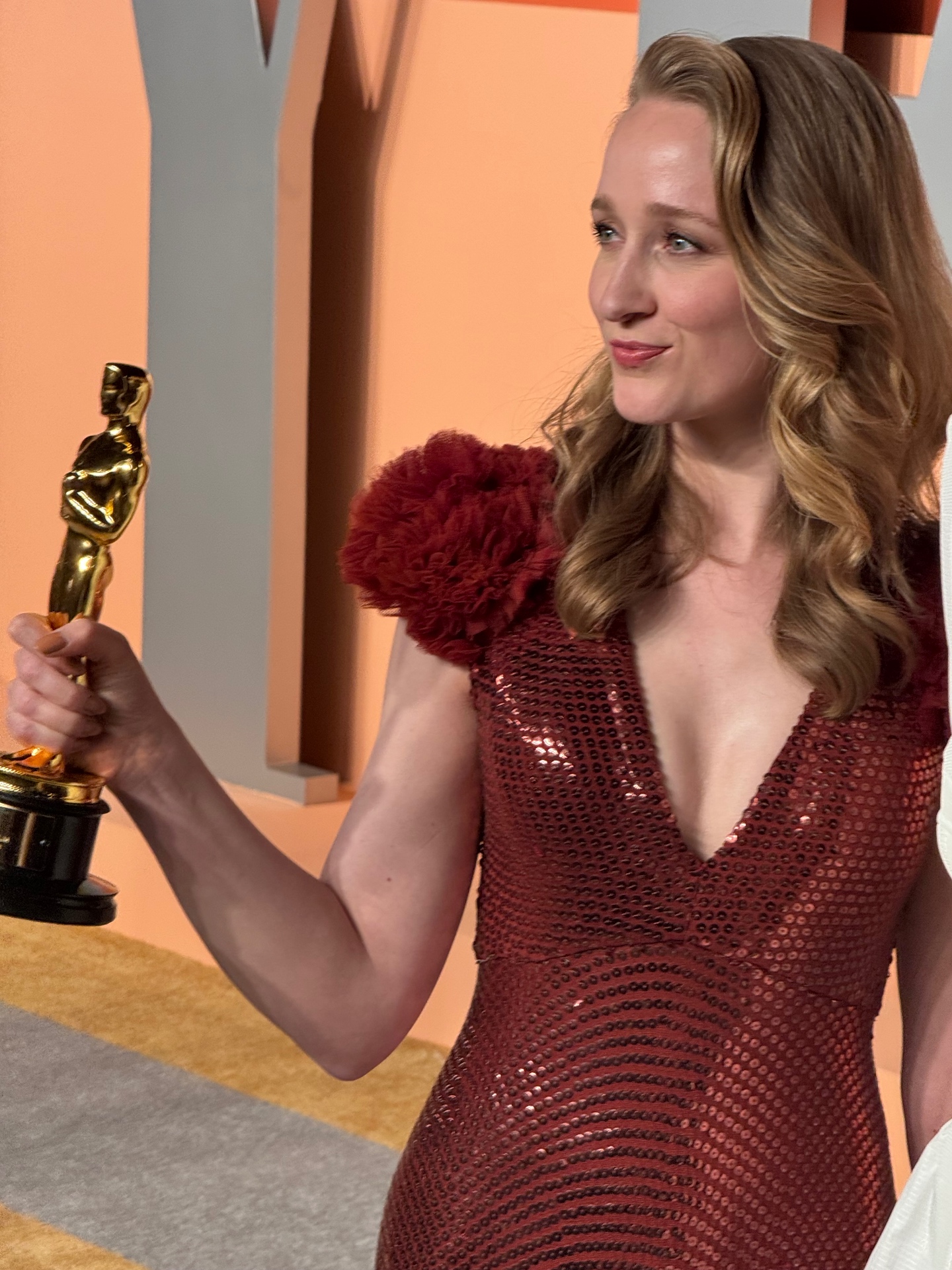 Oscar winner in red sequined gown holding her statuette